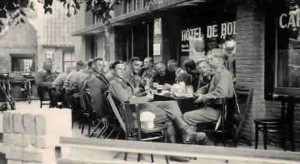 Duitse soldaten vermaken zich prima op het terras van Hotel de Boer (thans Hotel de Jong) in het centrum van Nes. Aan tafel bevindt zich ook pastoor H.C. Koelman. Hij verliet in 1940 het eiland en werd opgevolgd door pastoor Wilhelmus Hermanus Kaalberg die tot 1950 op het eiland zou blijven. Pastoor Kaalberg vinden we ook op de foto genomen van de aankomst van de bevrijders bij het gemeentehuis in Nes. Daar staat hij bij met andere mensen die deelnamen aan het verzet op het eiland.  (foto 25 augustus 1940)