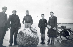 Een groepje eilanders poseert bij een op het strand aangespoelde zeemijn. Waarschijnlijk is de foto genomen tijdens de mobilisatie. (foto 23 september 1939)