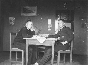 Twee soldaten zitten in burgerkleding aan een tafeltje in een café wat te eten en drinken. Foto gemaakt tijdens het eerste jaar van de bezetting. (foto 15 oktober 1940)