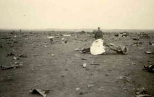 Een Duitse soldaat poseert bij de wijd verspreide wrakstukken van de op 19 februari 1943 gecrashte bommenwerper Short Stirling op het Neerlands Reid aan de oostkant van Ameland. Het vliegtuig werd door een nachtjager neergeschoten. De gehele bemanning verloor het leven. (foto 22 februari 1943)
